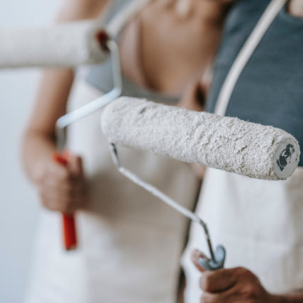 Paint & SuppliesPeople holding paint rollers with white paint, wearing aprons. The scene suggests home renovation, conveying a collaborative and productive atmosphere.